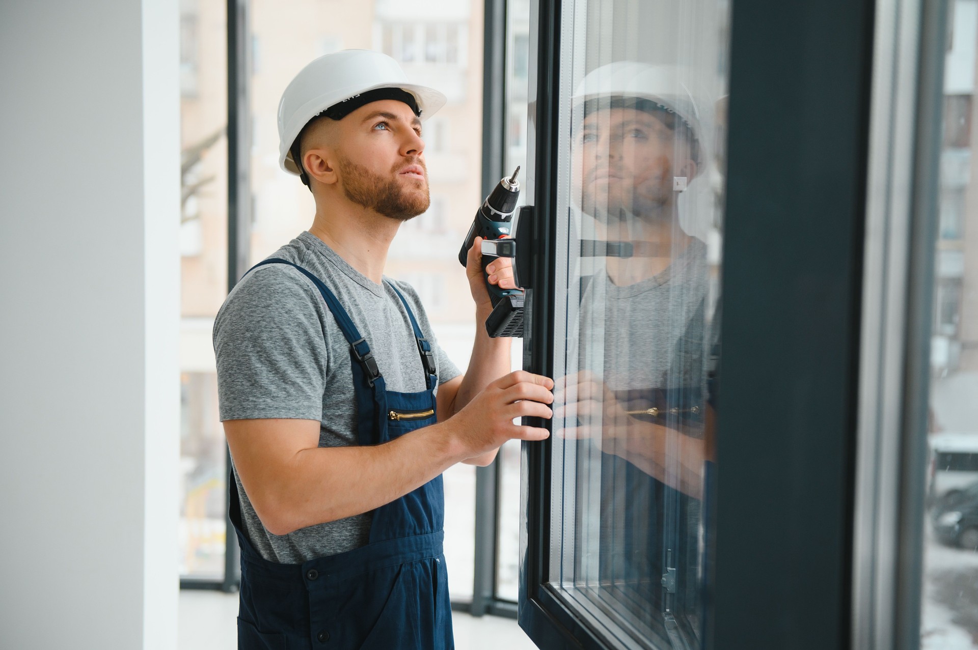Construction worker repairing plastic window with screwdriver indoors, space for text. Banner design